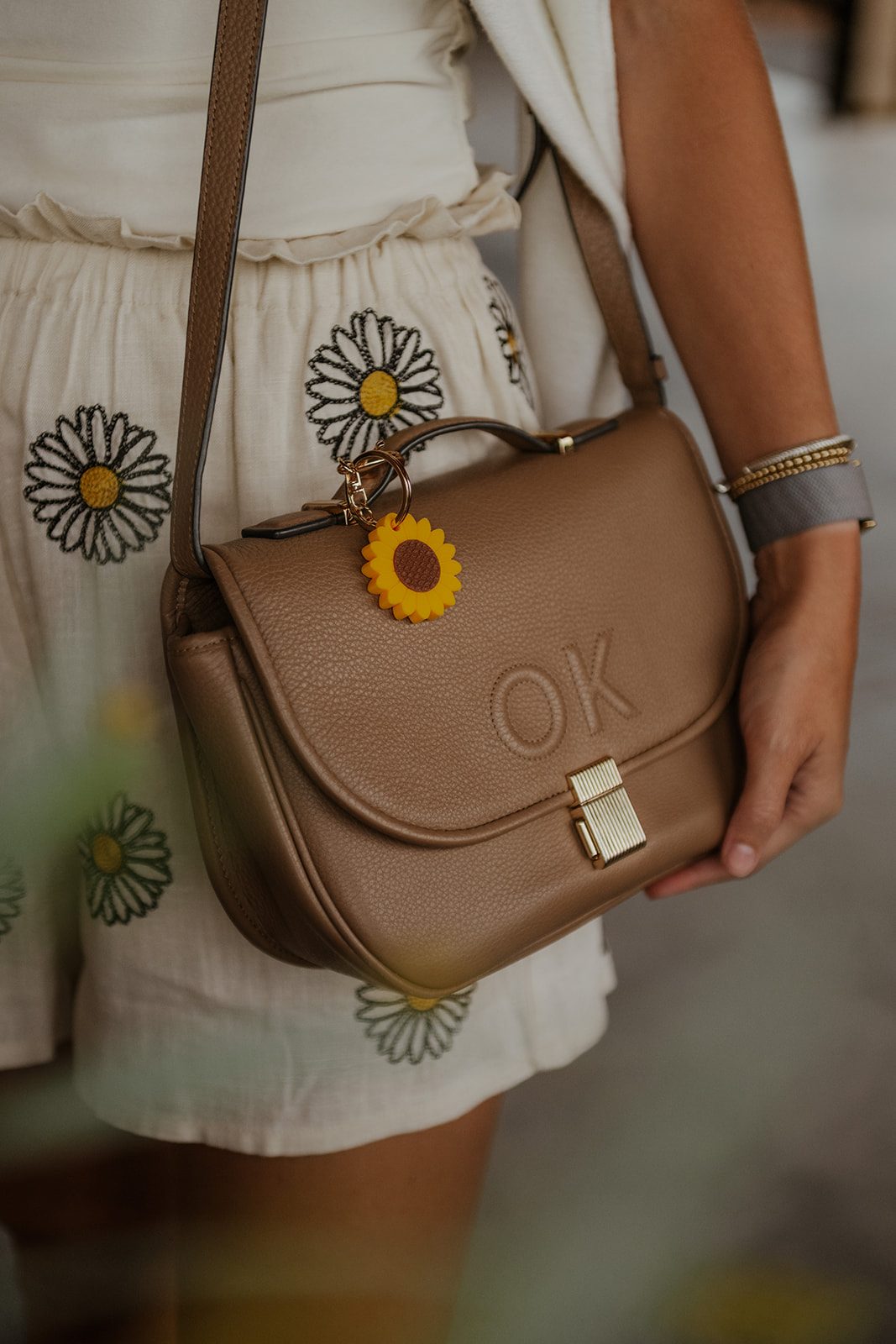 A sunflower TapLoop keychain clipped to a leather bag
