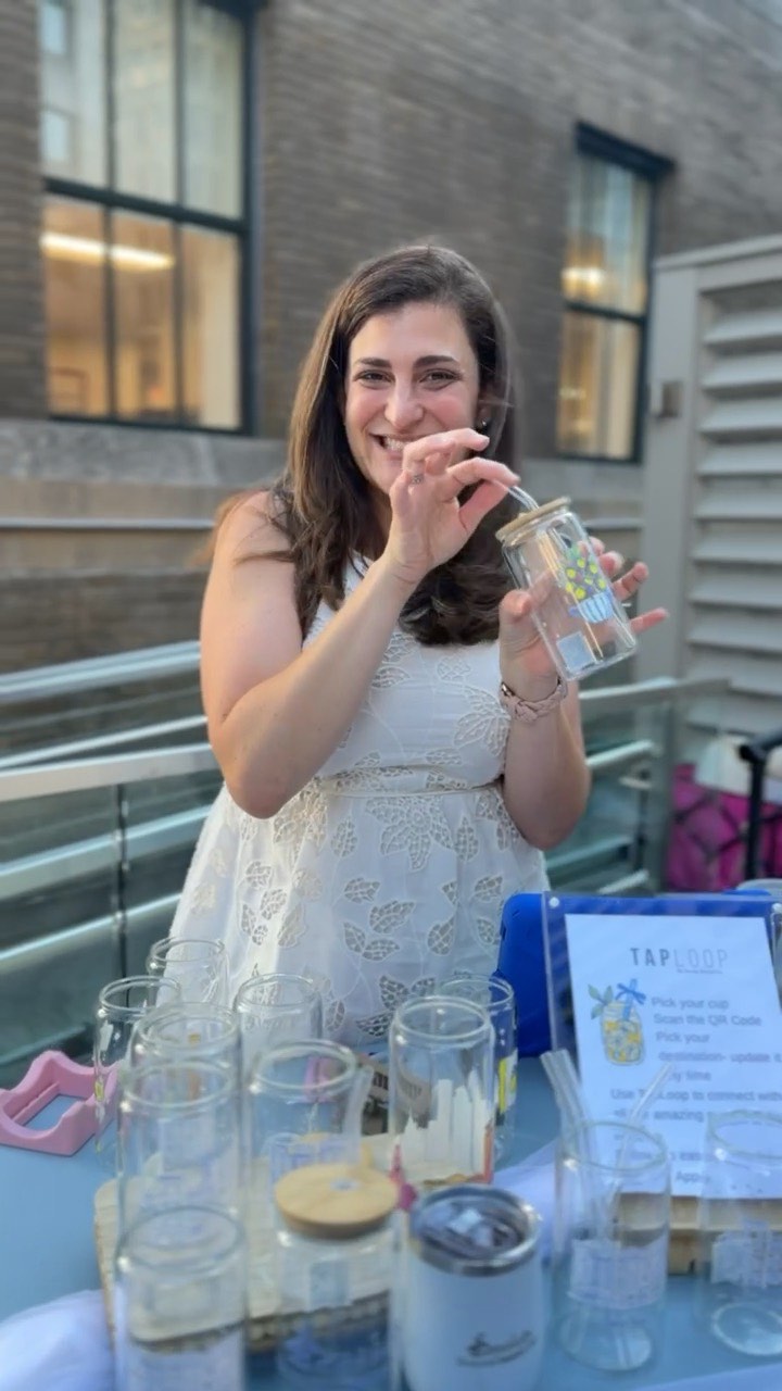 Someone smiling and holding their own personalized TapLoop tumbler at an event