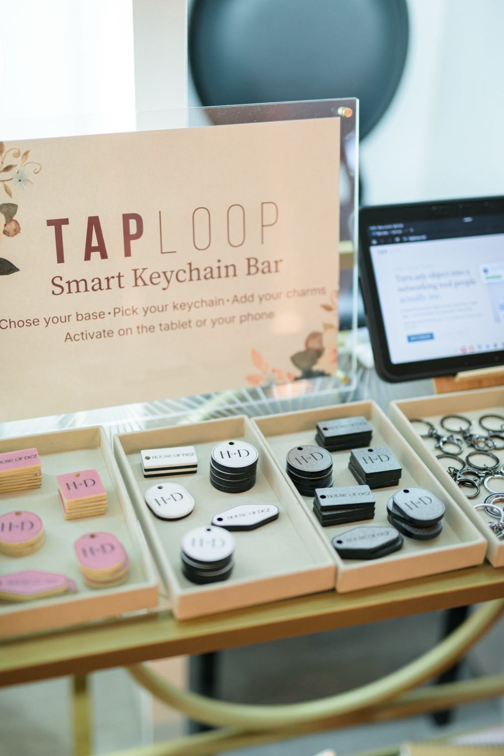 The TapLoop Smart Keychain Bar at House of Dez — trays of branded keychains, signage, and the activation tablet