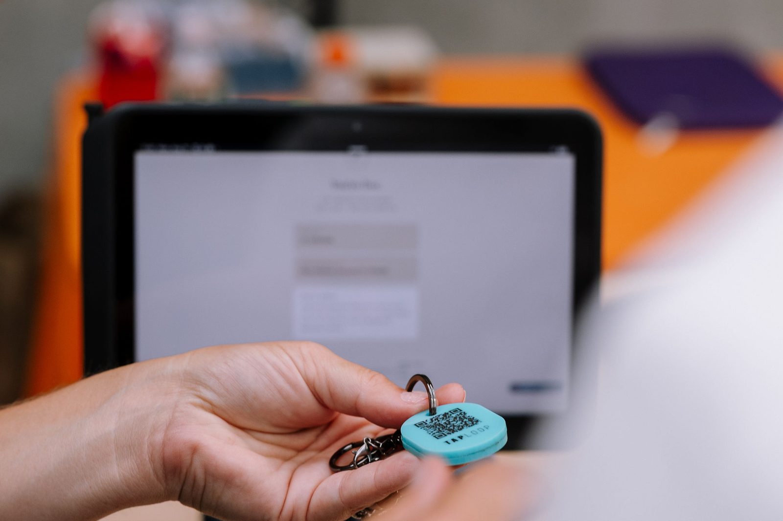 A TapLoop keychain held in front of the activation tablet at the keychain bar