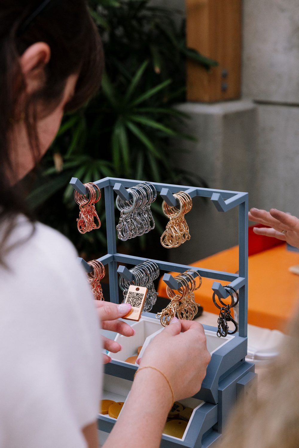 A guest building her TapLoop at the keychain bar — picking keyrings from the rack