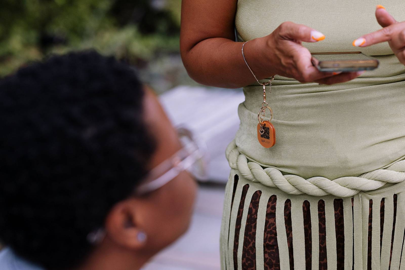 A guest wearing her TapLoop keychain clipped to her dress while showing her phone